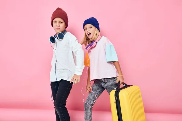 Komik küçük oğlan ve kız şık kıyafetler bavul kulaklık çocukluk yaşam tarzı konsepti — Stok fotoğraf