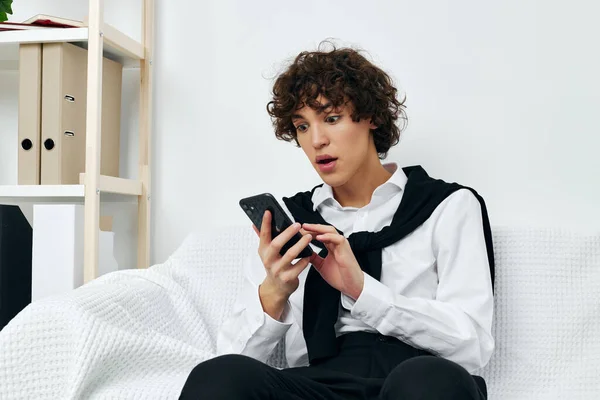 Blogger sitting on a white sofa smartphone communication — Fotografia de Stock