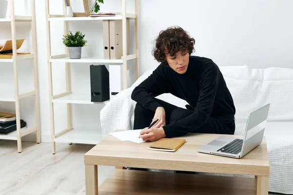 Curly guy on a white sofa in front of a laptop learning communication — 图库照片