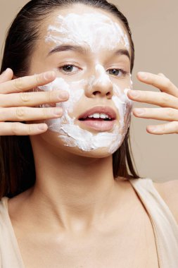 Göz çevresindeki yanaklarında nemlendirici olan esmer, bej arkaplan.