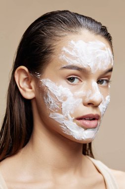 Kadın cilt bakımı yüz bej arka planda beyaz maske kullanarak