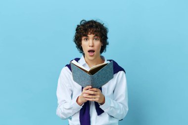 Omuzlarında süveter gömlekli bir not defteri olan bir öğrenci, izole edilmiş bir arka plan.