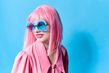 Mavi gözlüklü çekici kadın değiştirilmemiş pembe peruklu stüdyo modeli takıyor.