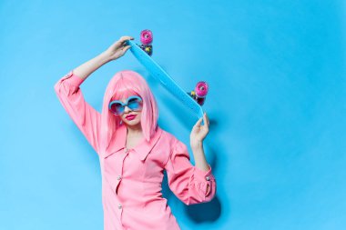 Güneş gözlüklü bir kadının portresi değiştirilmemiş pembe peruklu bir stüdyo modeli takıyor.