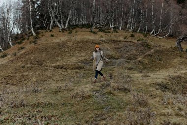 Sonbahar ormanındaki kadın temiz hava seyahati arazisinde yürüyor.