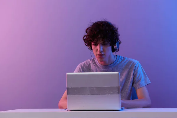 Kudrnatý chlap sedí u stolu herní notebook izolované pozadí — Stock fotografie