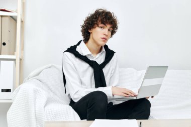 Masadaki koltukta oturan kıvırcık çocuk dizüstü bilgisayarın önünde yaşam tarzı teknolojisi.