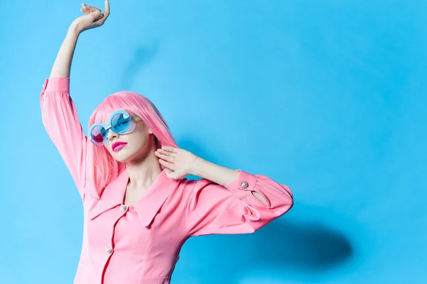 Mavi gözlüklü bir kadının portresi değiştirilmemiş pembe peruklu bir stüdyo modeli takıyor. — Stok fotoğraf