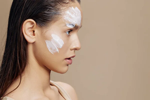 Kadın cilt bakımı yüz bej arka planda beyaz maske kullanarak — Stok fotoğraf