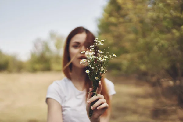 Donna romantica con un mazzo di fiori selvatici vicino agli alberi in un campo nella natura — Foto Stock