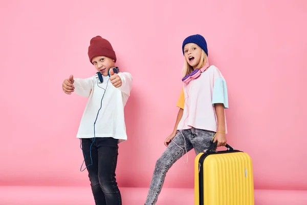 Χαρούμενη αγόρι και κορίτσι κίτρινη βαλίτσα με ακουστικά Παιδικός τρόπος ζωής έννοια — Φωτογραφία Αρχείου