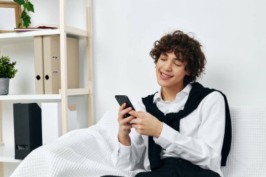 Kanepede telefonda internetten iletişim kurmayı öğrenen kıvırcık çocuk.