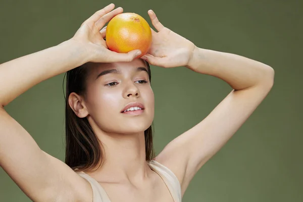 Brünette mit Grapefruit in Gesichtsnähe saubere Hautpflege Gesundheit grüner Hintergrund — Stockfoto