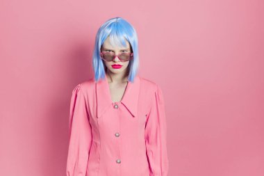 Mavi peruklu şık bir kadın. Pembe elbiseli, kırmızı dudaklı, stüdyo modeli.