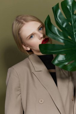 Palto giyen sarışın kadın kırmızı dudaklı moda yaprağı izole edilmiş arka plan