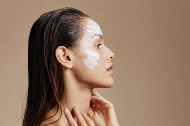 Yanaklarında nemlendirici, göz makyajı olan genç bir kadın.