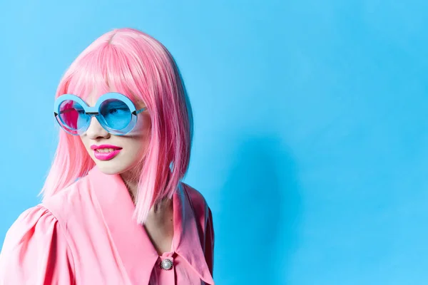 파란색 안경을 쓰고 있는 유행하는 여성은 핑크 색 가발을 외진 배경에 쓰고 있다 — 스톡 사진