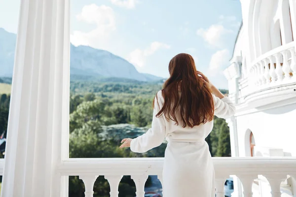 Bella donna vestaglia bianca ammirare la vista dalla finestra inalterata — Foto Stock