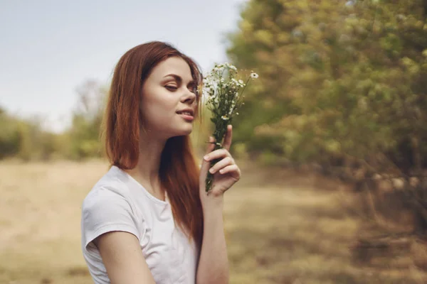 Mujer con flores blancas en la mano está descansando en el campo y los árboles en el estilo de vida de fondo —  Fotos de Stock