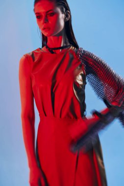 Genç kadın Glamor kırmızı ışıklı metal zırh poz veriyor.