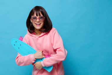 Genç bayan mavi kaykay izole edilmiş eğlenceli bir zemin oluşturuyor.