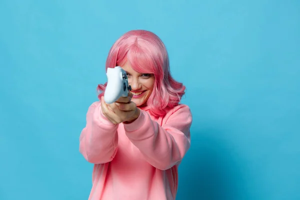 Mujer joven con gamepad rosa sudadera entretenimiento fondo azul — Foto de Stock