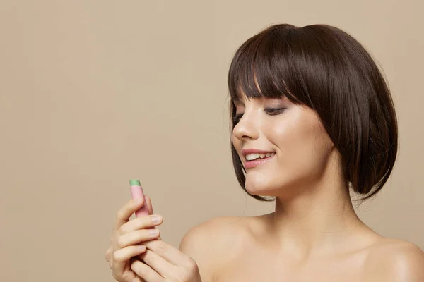 Schöne Frau Make-up Lippenstift in der Hand Modell posiert beige Hintergrund — Stockfoto