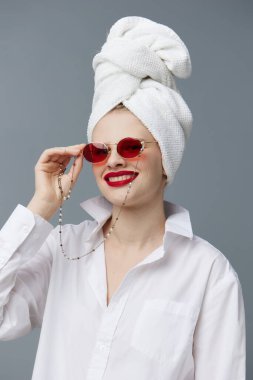 Kafasında havlu olan beyaz gömlekli bir kadın. Stüdyo modeli değiştirilmemiş.