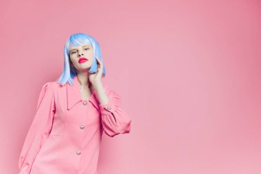 Mavi peruklu şık bir kadın. Pembe elbiseli. Kırmızı dudaklı.