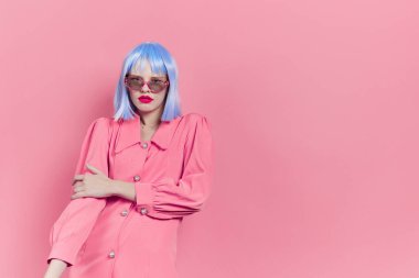 Güneş gözlüklü güzel bir kadın mavi bir peruk takıyor.