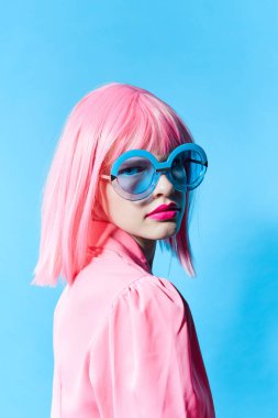 Mavi gözlüklü güzel bir kadın pembe peruklu stüdyo modeli takıyor.