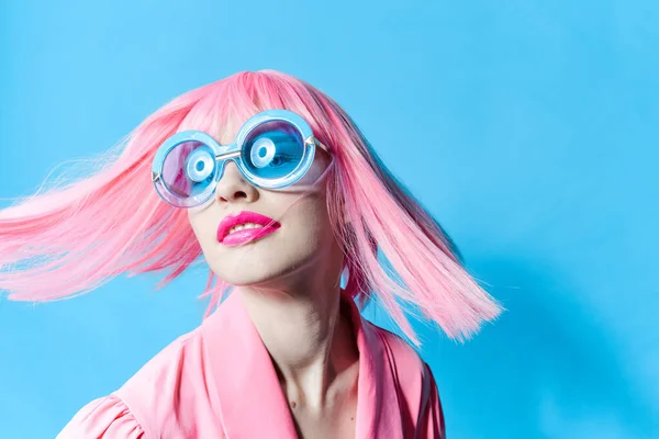Όμορφη γυναίκα με μπλε γυαλιά φοράει μια ροζ περούκα απομονωμένη φόντο — Φωτογραφία Αρχείου