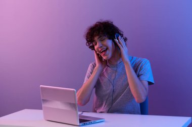 Dizüstü bilgisayarın önünde kulaklıklı kıvırcık adam. Hayat tarzı teknolojisi.