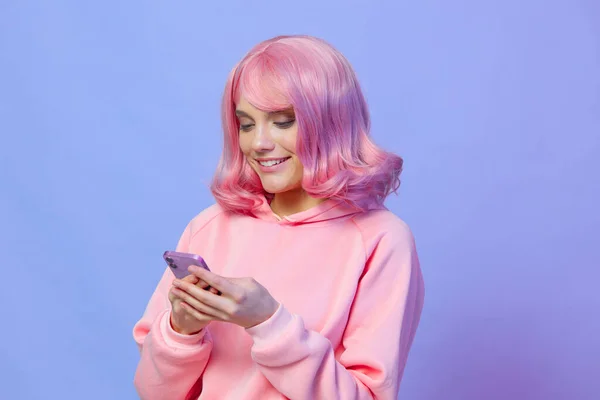 Piękna kobieta trzyma telefon pozowanie technologii fioletowy tle — Zdjęcie stockowe