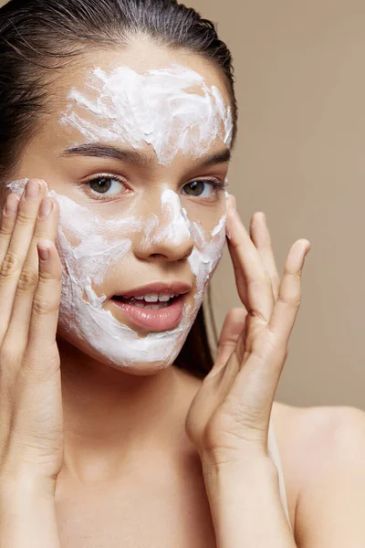 Ung kvinna ansikte mask grädde ren hud ansiktsskrubb beige bakgrund — Stockfoto