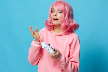 Oyunun elinde joystick ile mavi arka plan pozu veren bir kadın.
