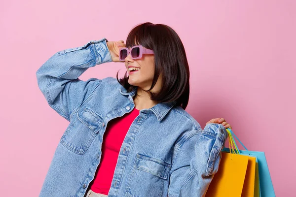 Bela mulher em jaquetas de ganga com colorido sacos de compras isolado fundo — Fotografia de Stock