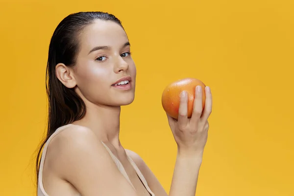 Porträtt kvinna grapefrukt i händerna poserar ren hud gul bakgrund — Stockfoto