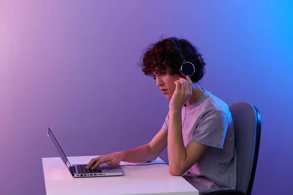 Cara encaracolado em fones de ouvido na frente de entretenimento laptop isolado fundo — Fotografia de Stock