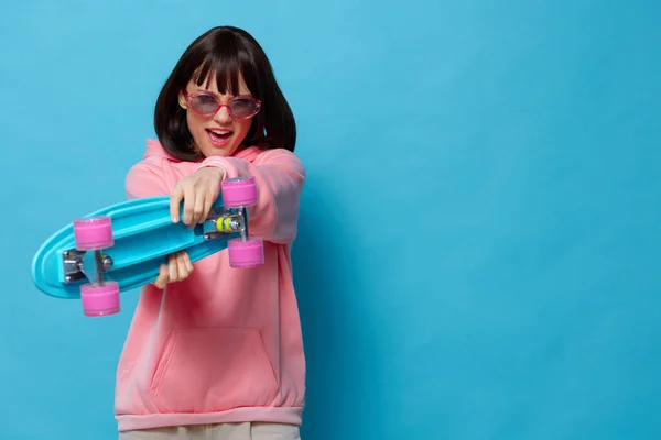 Retrato mujer en un suéter rosa skate entretenimiento fondo azul —  Fotos de Stock