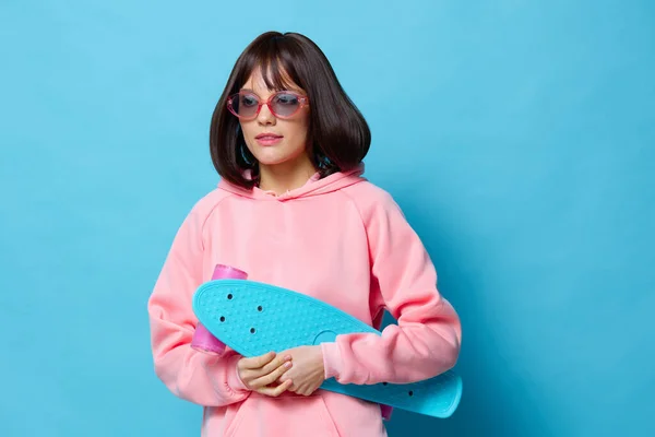 Молода жінка в рожевому светрі скейтборд розваги ізольований фон — стокове фото