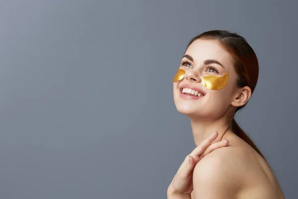 Jonge vrouw huidverzorging gezicht pleisters kale schouders geïsoleerde achtergrond — Stockfoto
