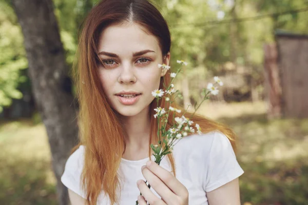 白いTシャツに野の花を手にした女性が草原で自然の上で — ストック写真