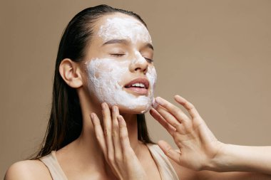 Genç bir kadın rahatlatıcı bir yüz maskesi takıyor. Kozmetik yakın çekim.