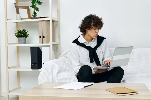Man op een witte bank in de voorkant van een laptop leren woonkamer — Stockfoto