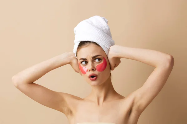 Młoda kobieta z ręcznikiem na głowie gestykulując dłońmi pielęgnacja skóry beżowe tło — Zdjęcie stockowe