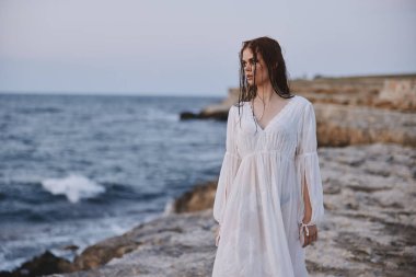 Çekici kadın beyaz elbisesi açık havada duruyor.