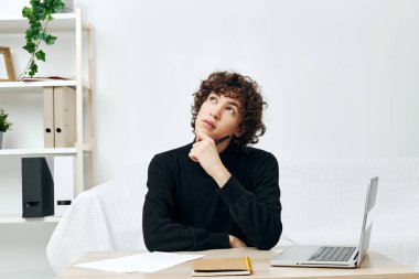 Genç dizüstü bilgisayar beyaz koltukta oturuyor online yaşam tarzı eğitimi alıyor.