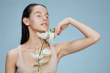 Esmer, mavi arka planda yüzünün yanında orkide var. Yüksek kalite fotoğraf