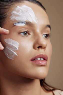 Yanağında nemlendirici ve yakın çekim makyajı olan güzel bir kadın. Yüksek kalite fotoğraf
